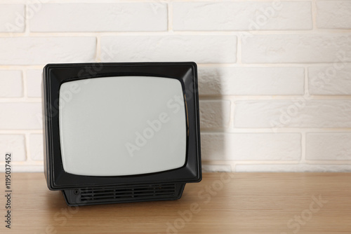 Retro tv set on wooden shelf against white brick wall. Space for text photo