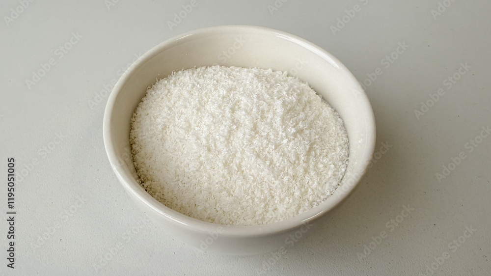 A bowl of shredded coconut on a white background, ideal for baking concepts and tropical-themed holiday recipes A bowl of shredded coconut on a white background, ideal for baking concepts and tropical-themed holiday recipes