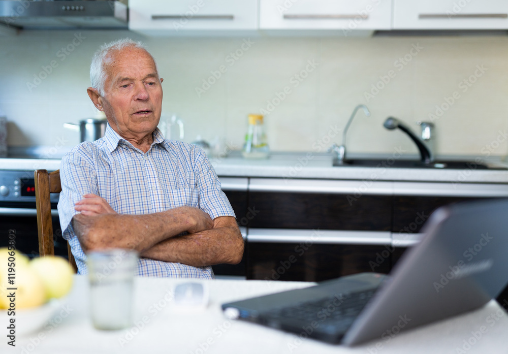 Old man sitting and looking at his laptop Old man sitting and looking at his laptop