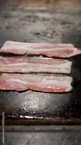 Watch the sizzle of raw bacon transforming into golden, crispy perfection on the grill. Perfect for breakfast, burgers, or snacks, these bacon strips are irresistible