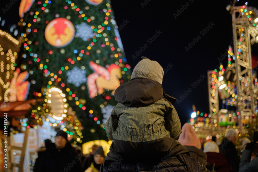 A man rolls a child on his shoulders during the Christmas holidays A man rolls a child on his shoulders during the Christmas holidays