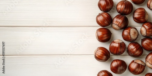 Fresh shiny chestnuts in rich brown shades scattered on a light wooden table background with ample space for text on the left side photo