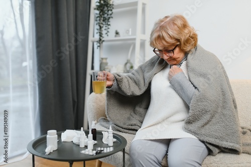 Caucasian ill mature woman sits on home sofa, looking tired upset. Treatment of colds and flu at home. photo