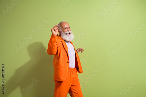 Photo of funny showman dance empty space wear orange suit isolated on green color background photo