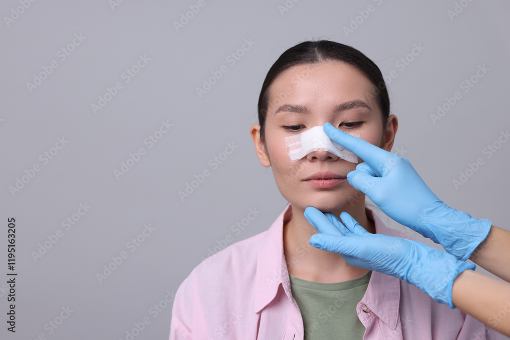 Doctor checking patient's nose after plastic surgery operation on light grey background, closeup. Space for text Doctor checking patient's nose after plastic surgery operation on light grey background, closeup. Space for text