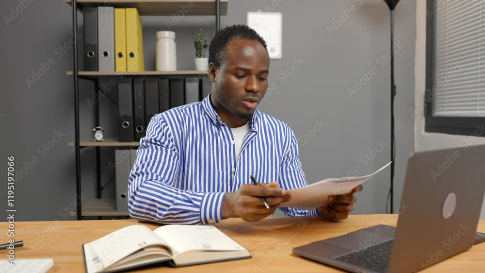 Man sitting at desk holding paper Man sitting at desk holding paper