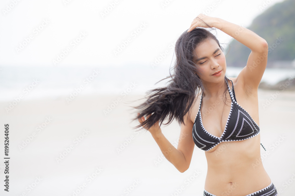 Naklejka premium Beautiful young asian woman standing with happiness for relax on beach in tropical, happy woman in bikini with expression relaxation in holiday with seductive, recreation and leisure in summer.