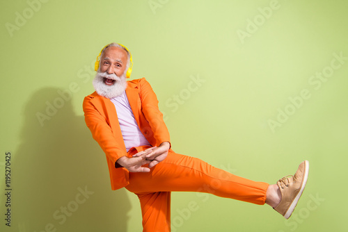 Photo of funny showman have fun headphones music wear orange suit isolated on green color background photo