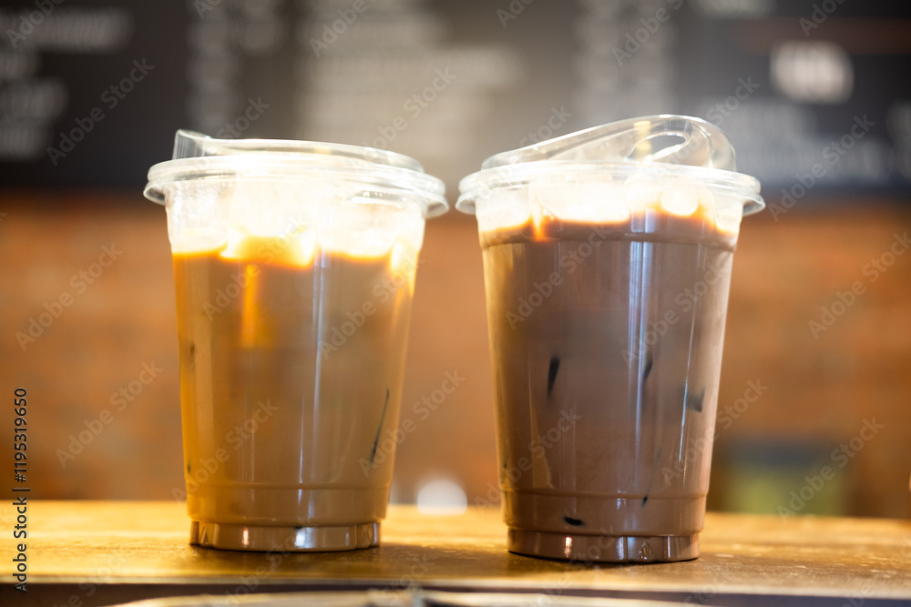 Two takeaway glasses filled with cold coffee with ice cubes on table Two takeaway glasses filled with cold coffee with ice cubes on table