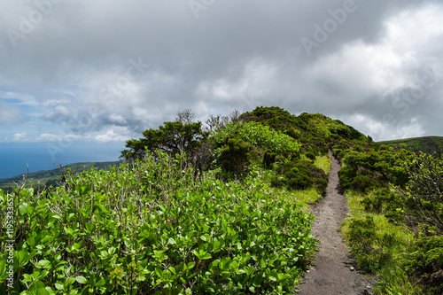 Crater of Vulcão da Caldeira or The Caldeira Volcano on Faial Island, the Azores, in the Atlantic Ocean. Stratovolcano with a lake inside the crater. Low clouds. Hiking around volcano. photo