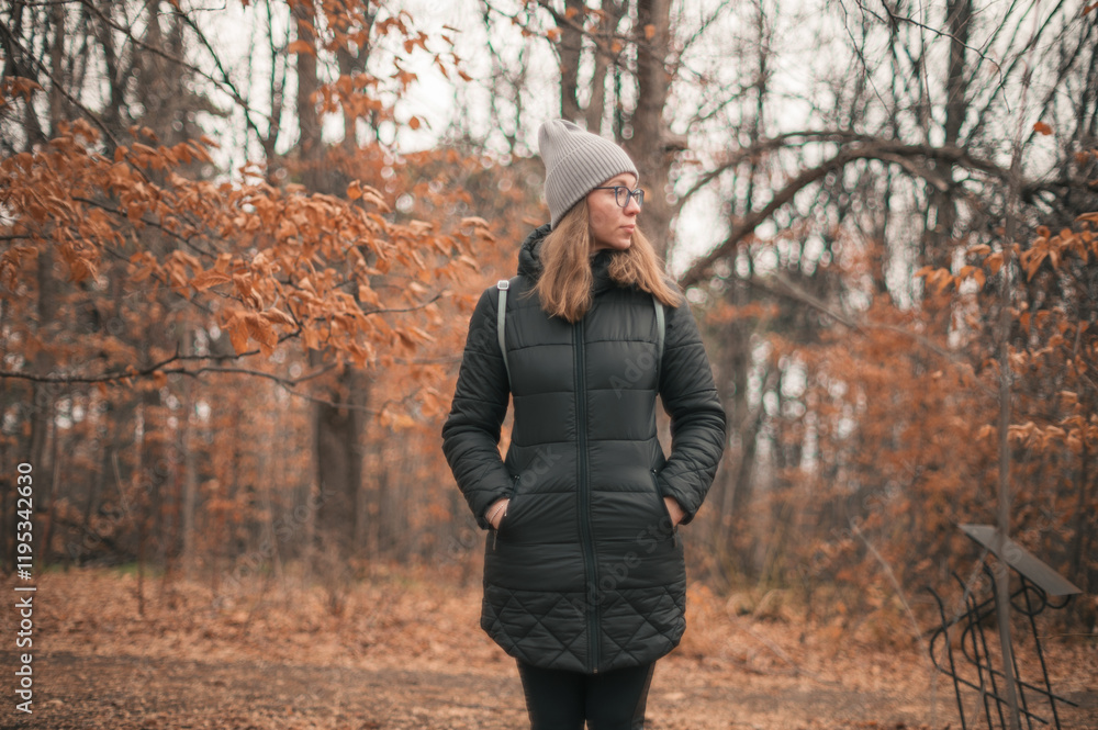A woman dressed in a beanie and jacket standing in a forest with golden autumn leaves, conveying a cozy seasonal vibe. A woman dressed in a beanie and jacket standing in a forest with golden autumn leaves, conveying a cozy seasonal vibe.