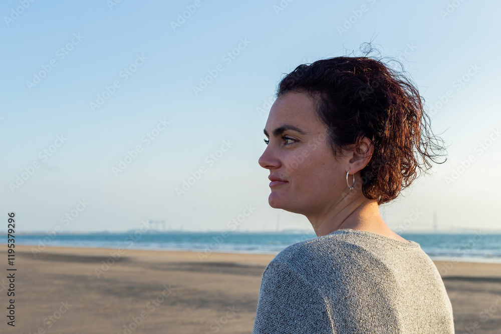 Portrait of a young woman with curly hair at sunset on the beach
