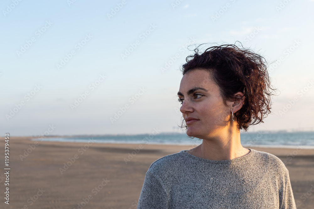Portrait of a young woman with curly hair at sunset on the beach Portrait of a young woman with curly hair at sunset on the beach