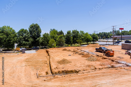 Heavy machinery is shaping land in trenches for foundation at construction site under works area photo