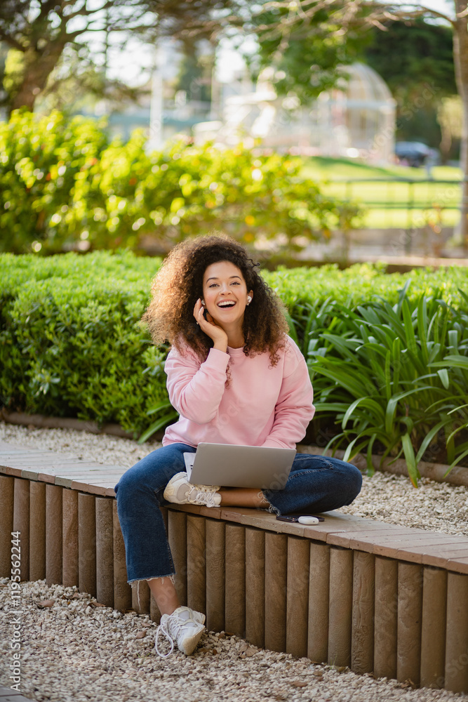 pretty curly young woman sitting in park working on laptop remote job pretty curly young woman sitting in park working on laptop remote job