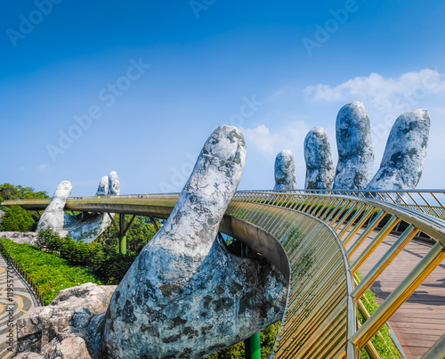 Golden Bridge in Ba Na hills, Da Nang, Vietnam on a sunny day. Lifted by two giant concrete hands. Iconic world famous bridge in the mountains