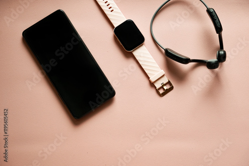 Wireless open ear headphones, smartwatch and mobile phone on a pink background. Technology and electronics. Modern gadgets. Sports.