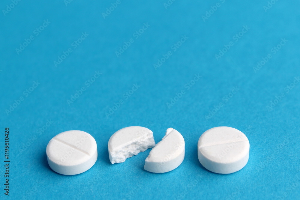 There are white round tablets on a blue background. There are white round tablets on a blue background.