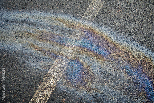 Slick surface in a parking space, revealing an oil spill from an automobile, delineated by a white marking. photo