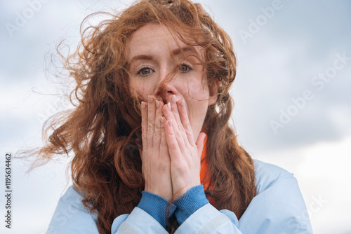 Foto Woman with windblown hair expressing surprise outdoors during cloudy day