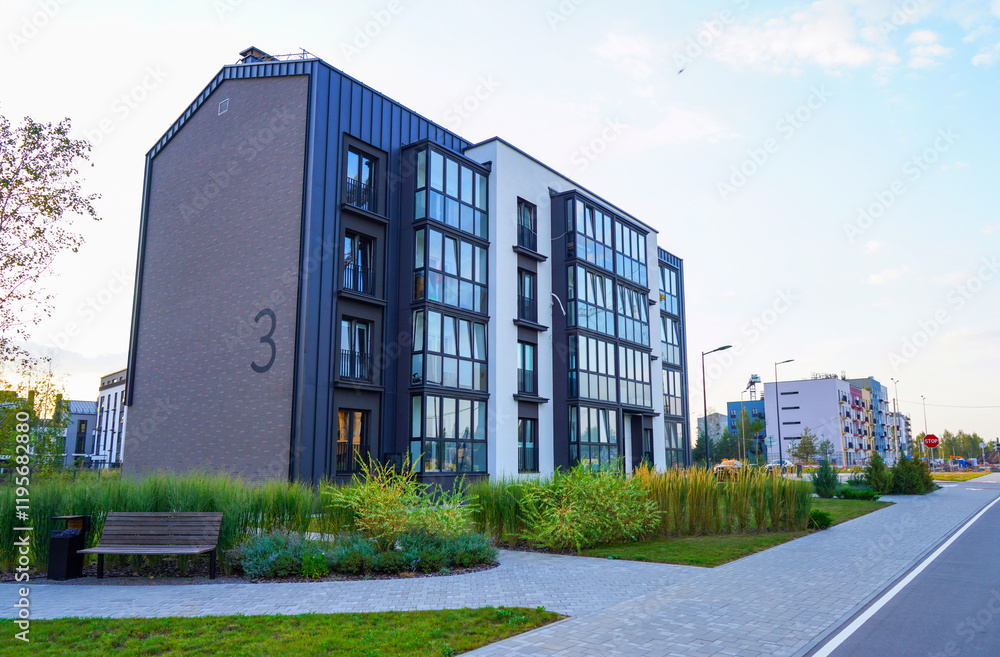 Obraz premium Modern complex building. Street with road and sidewalk. New apartment buildings in green enviroment. Landscaping for urban spaces. Building exterior, house block. Condominium in residential area.