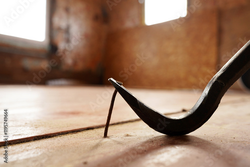 Nail puller pulls a Iron Nail out of the wooden board. Removing a Iron Nail with a nail puller from a wooden floorboard in a house.