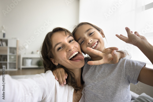 Canvas Print Happy mom and little daughter fooling, having fun, looking at camera, showing gestures and tongue looks playful, spend time record videos for social media platform