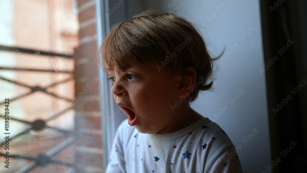 Baby yawning next to window in the morning. Toddler yawns waking up in the morning Baby yawning next to window in the morning. Toddler yawns waking up in the morning