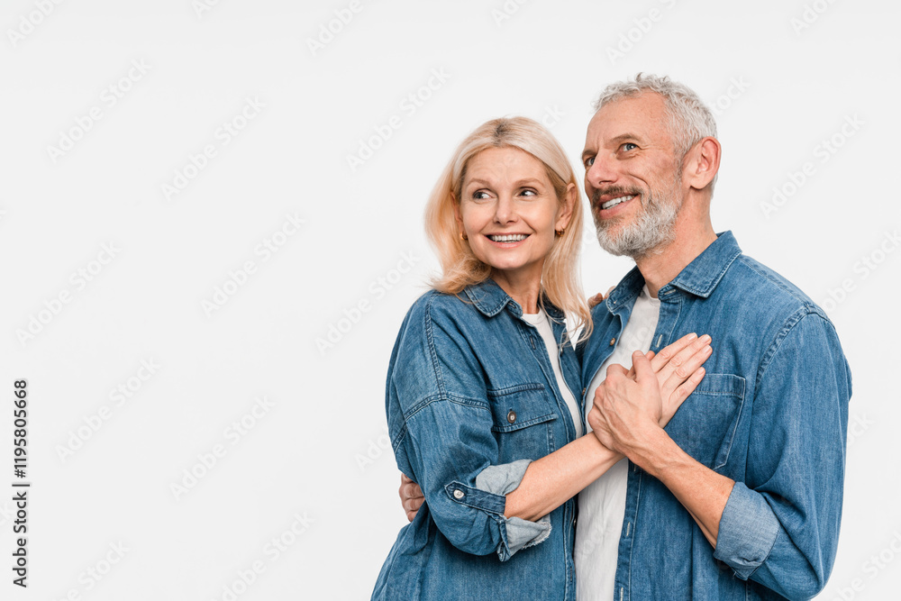 Cheerful smiling funny couple family elderly gray-haired man blonde woman in denim shirt casual clothes standing hugging looking dreamy aside isolated on white background studio portrait copy space Cheerful smiling funny couple family elderly gray-haired man blonde woman in denim shirt casual clothes standing hugging looking dreamy aside isolated on white background studio portrait copy space