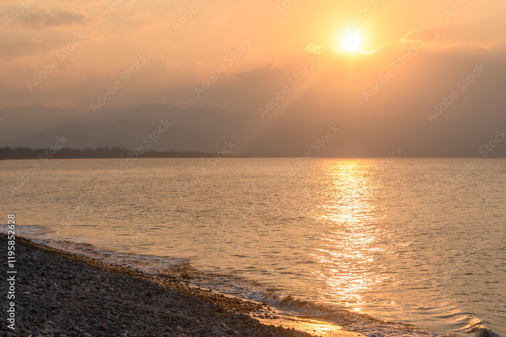 Sunset paints the sky with warm hues over a tranquil shoreline at dusk Sunset paints the sky with warm hues over a tranquil shoreline at dusk