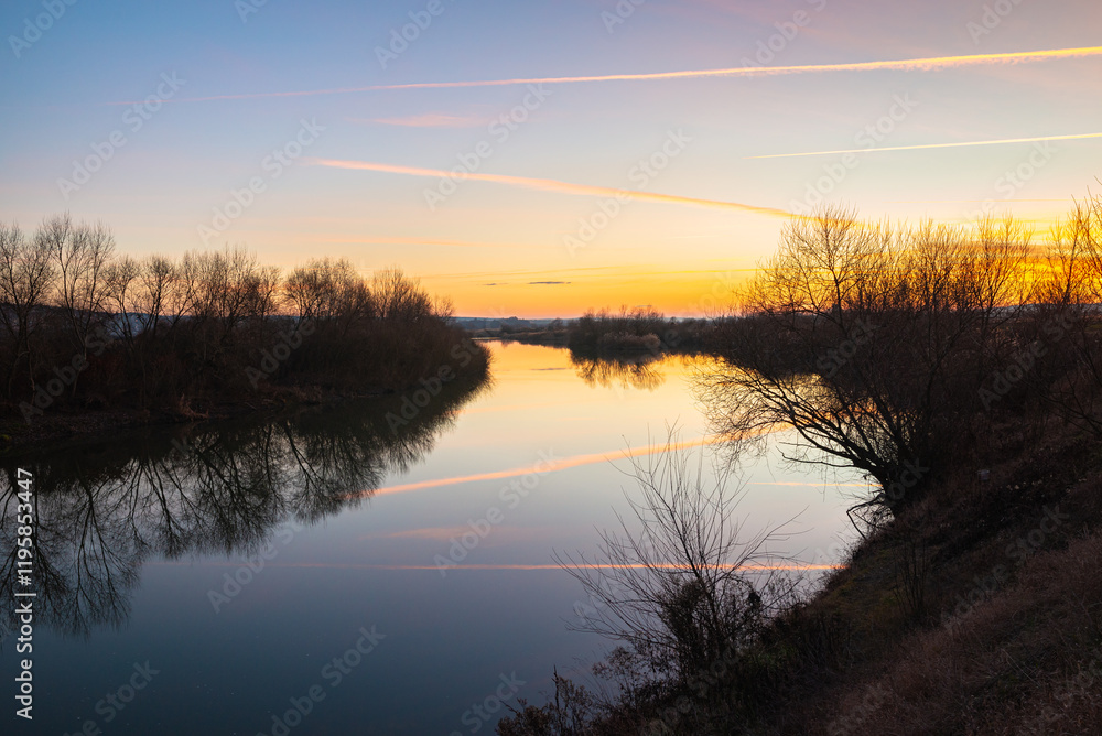 Soothing view of a colorful sunset over the calm waters of the Mures River in Transylvania, central Romania on a clear winter day Soothing view of a colorful sunset over the calm waters of the Mures River in Transylvania, central Romania on a clear winter day