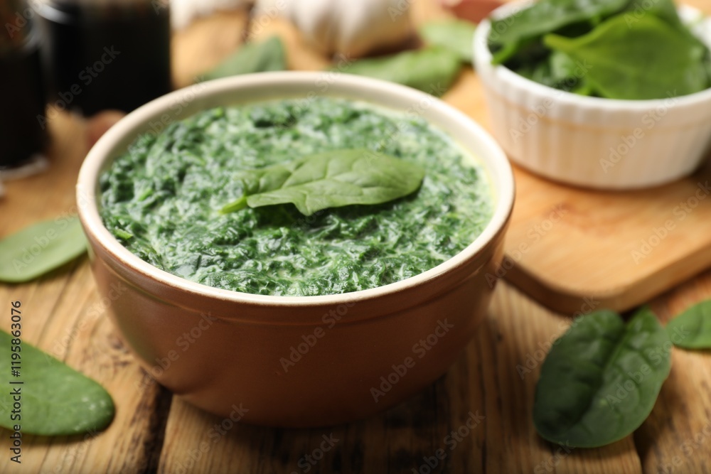 Delicious spinach sauce in bowl and leaves on wooden table, closeup Delicious spinach sauce in bowl and leaves on wooden table, closeup