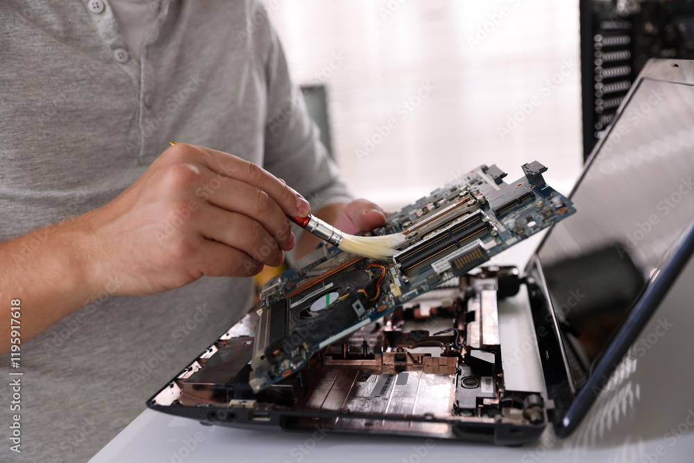 Man cleaning motherboard with brush at white table, closeup Man cleaning motherboard with brush at white table, closeup