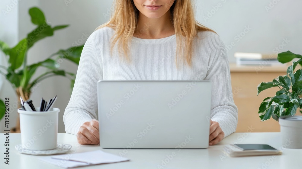 Fototapeta premium Young woman working on a laptop at a bright and cozy home office with plants and stationery around her