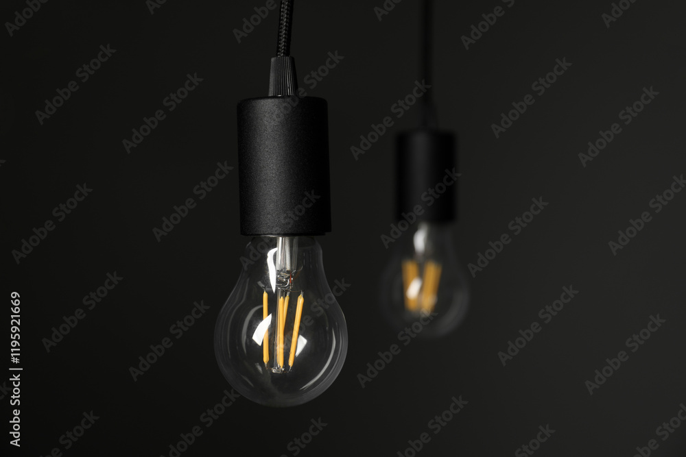 Light bulbs hanging on cords against grey background, selective focus. Space for text Light bulbs hanging on cords against grey background, selective focus. Space for text