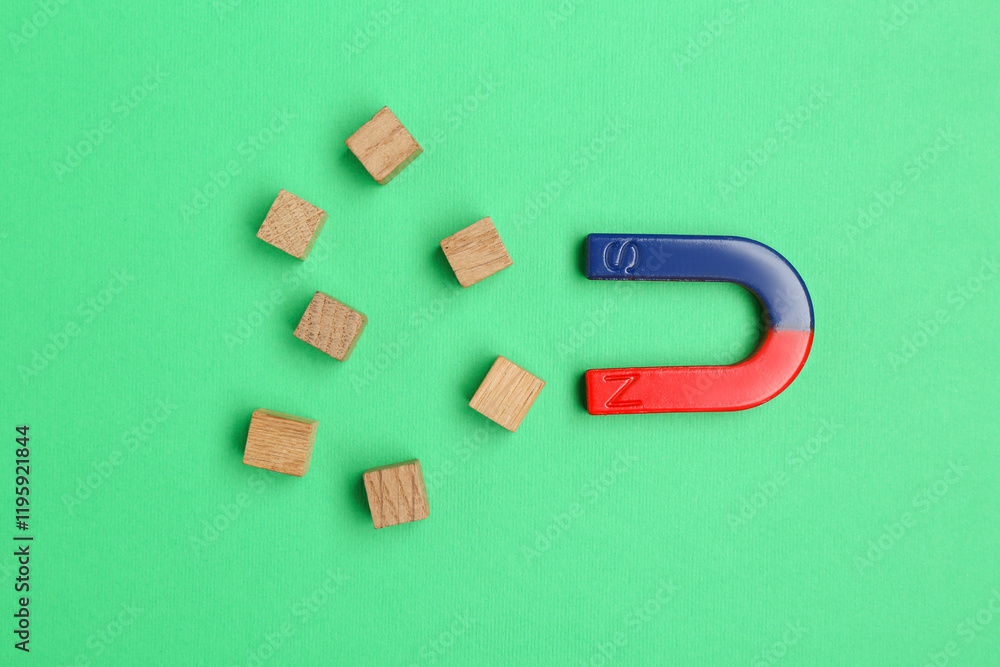Magnet attracting wooden cubes on green background, flat lay Magnet attracting wooden cubes on green background, flat lay
