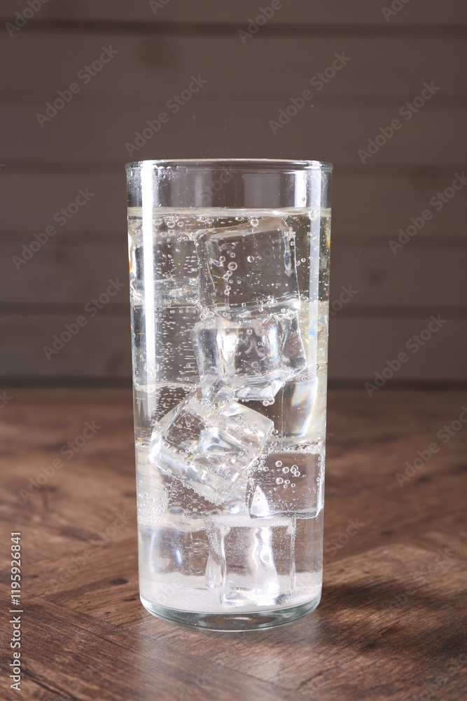 Refreshing soda water with ice cubes in glass on wooden table, closeup Refreshing soda water with ice cubes in glass on wooden table, closeup