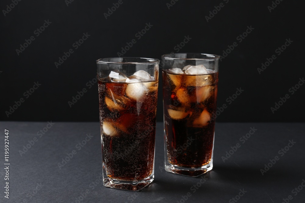 Refreshing cola with ice cubes in glasses on black table, closeup Refreshing cola with ice cubes in glasses on black table, closeup