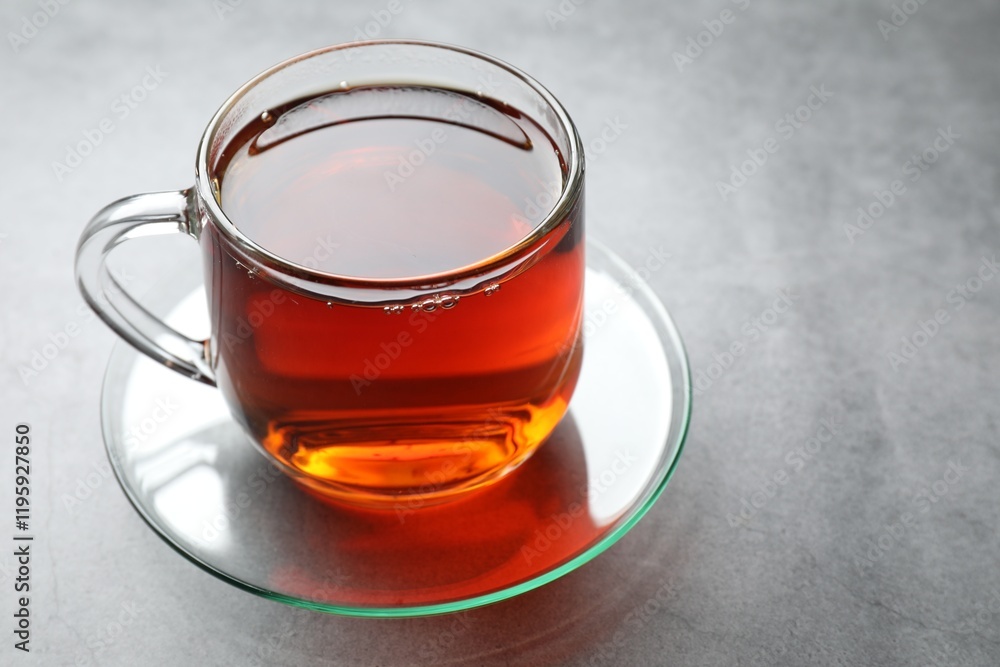 Refreshing black tea in cup on grey textured table, closeup. Space for text Refreshing black tea in cup on grey textured table, closeup. Space for text
