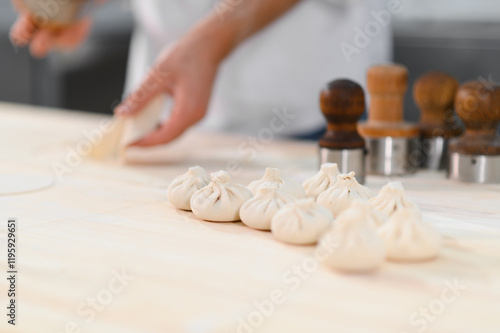 A cook rolls out dough pieces to make traditional Georgian khinkali in a kitchen. This image captures the preparation process of popular dumplings, showcasing a culinary skill with flour and dough photo