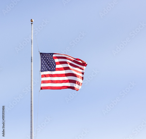 american flag at half mast against blue sky