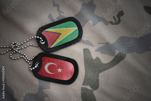 vintage army blank, dog tag with flag of guyana and turkey on the khaki texture background. military concept. photo