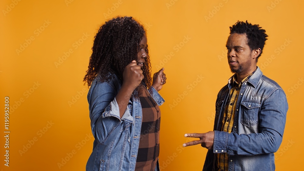 Cheerful positive married couple playing rock paper scissors in studio, having fun with a children activity and competition. Playful joyful man and woman trying to make a decision. Camera B. Cheerful positive married couple playing rock paper scissors in studio, having fun with a children activity and competition. Playful joyful man and woman trying to make a decision. Camera B.