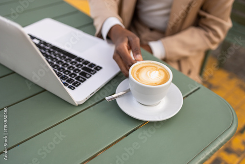 Urban black woman at a cafe with a laptop and coffee photo