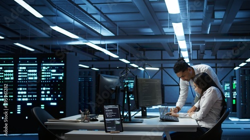 Photography Teamworking colleagues in high tech data center managing and maintaining databases, ensuring data integrity, security and availability