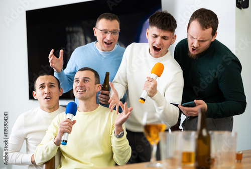 Fotografía Cheerful male friends having fun while singing karaoke at a bar