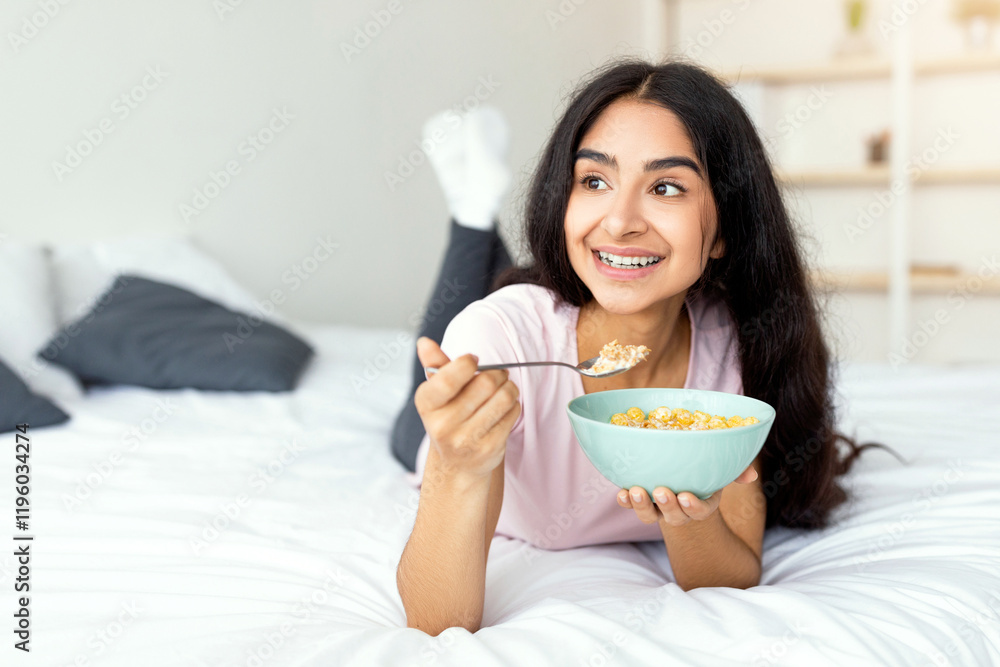 Portrait of fit Indian lady eating cereal with milk on bed at home. Young Hindu woman enjoying nutritious breakfast, keeping balanced diet for weight loss, taking care of her body, copy space Portrait of fit Indian lady eating cereal with milk on bed at home. Young Hindu woman enjoying nutritious breakfast, keeping balanced diet for weight loss, taking care of her body, copy space