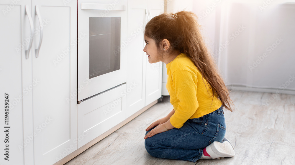 Cute little girl sitting near oven in kitchen and looking inside through glass, curious impatient female child waiting for cookies baking in stove, enjoying homemade pastry, side view, copy space Cute little girl sitting near oven in kitchen and looking inside through glass, curious impatient female child waiting for cookies baking in stove, enjoying homemade pastry, side view, copy space