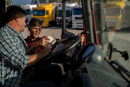 Truck driver having conversation with fleet manager before the trip, looking at paperwork 