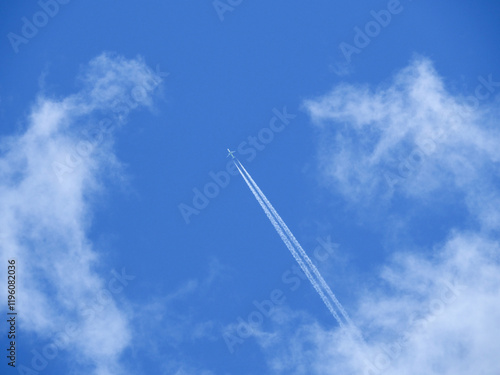 青空を上昇する白い飛行機と飛行機雲